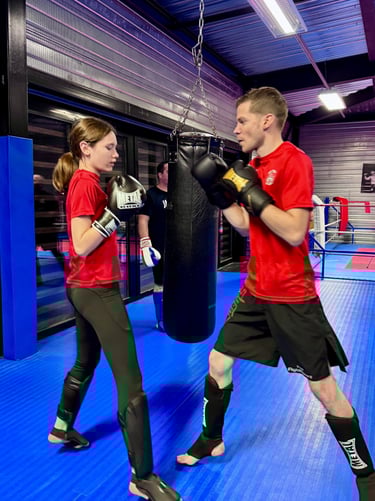 Entraînement de boxe : un homme et une jeune fille en garde, prêts à boxer