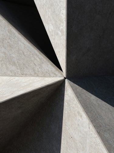 Macro close-up of sharp architectural concrete under harsh direct sunlight, casting deep geometric shadows.