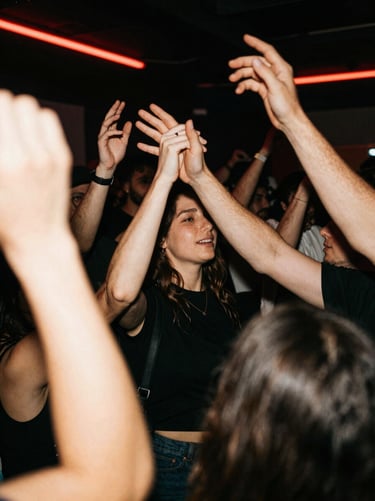 High-contrast nightlife photography, crowd dancing under red neon lights, hands in the air, motion blur, raw energy, 35mm film aesthetic