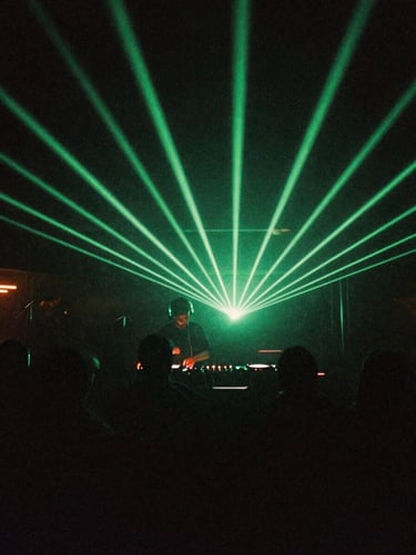 Moody low-light nightlife photography, neon green laser beams cutting through a dark club, DJ in motion behind decks, direct flash, 35mm film aesthetic