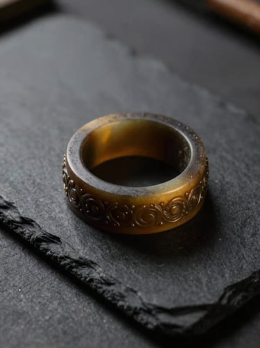 Extreme close-up of a master-carved wax ring mold on a dark slate workbench, side lighting