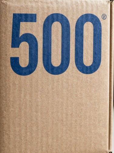 Physical brand collateral, a heavy cardboard packaging box with sharp blue technical typography, 50mm lens