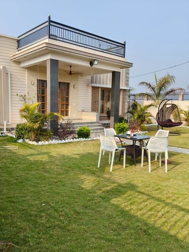 Modern luxury PG exterior featuring a green lawn with a patio dining set and a hanging egg chair.