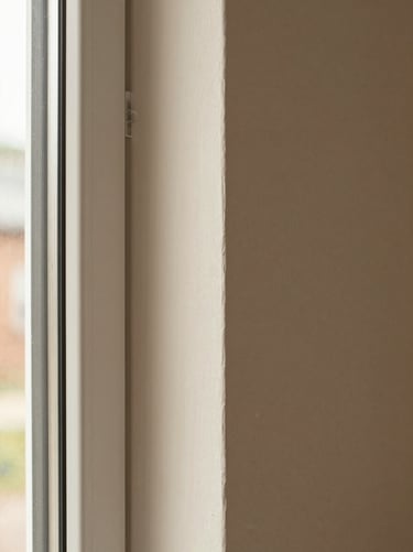 The same interior wall after remodel—smooth painted finish, new window casing with clean mitered corners, warm natural daylight, documentary close-up showing edge quality