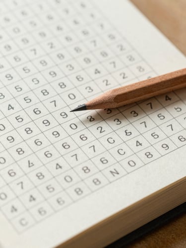 Close-up detail shot of an open word search book with clean grid lines, a sharp wooden pencil resting on the thick cream paper.