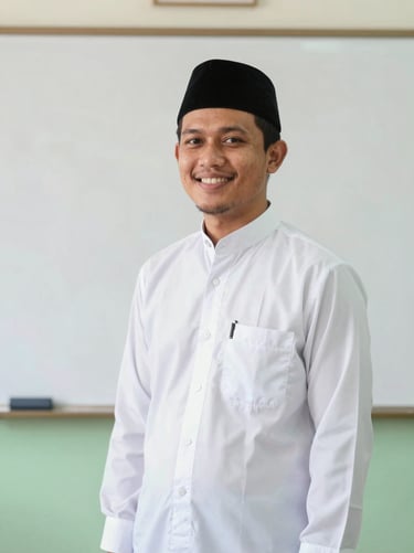 A smiling male Islamic teacher in a clean batik shirt standing in front of a white board.