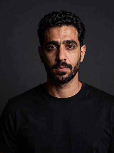 Dramatisches Schwarz-Weiß-Porträt von Ali Almadhlom unter hartem Studiolicht, Blick direkt in die Kamera, minimalistischer dunkler Hintergrund.