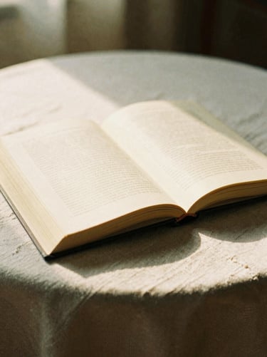 Still life of an open book on a linen tablecloth, soft golden hour light, warm film photography.