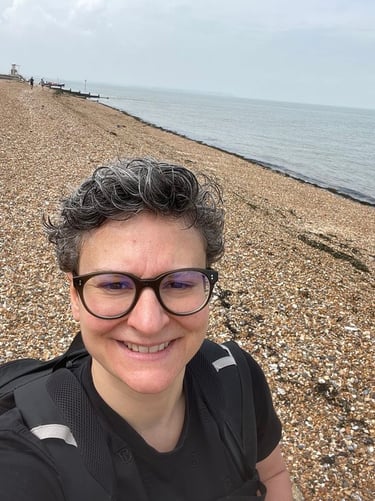 a woman with glasses and a backpack on a beach