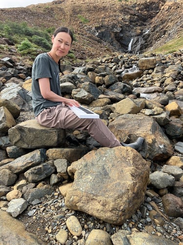 Composer Jen Smith Lanthier playing the keyboard outdoors in a natural setting