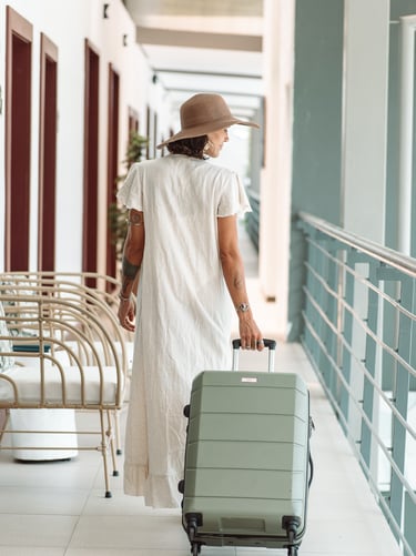 a woman in a white dress and hat, holding a suitcase in a hotel in costa rica