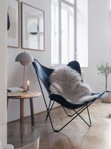 Zona de estar con decoración simple, un sillón moderno y mesita, tonos claros