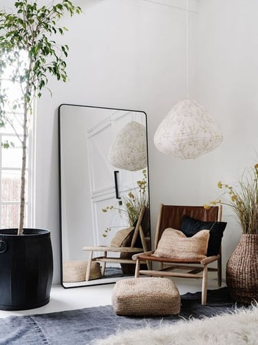 Interior de una habitación, con decoración minimalista, espejo, sofá, puff, lampara, alfombras