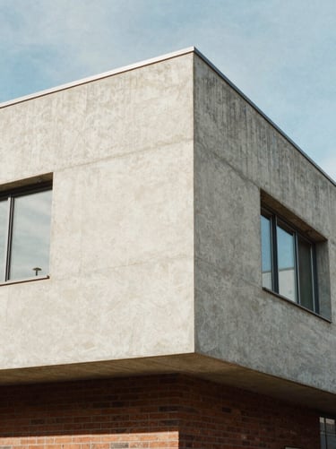Exterior detail of a modernist concrete and brick house with an asymmetrical facade, bright natural light.