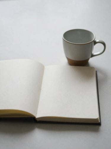 An open notebook with clean pages beside a ceramic cup, soft overcast morning light, minimalist film photography, muted earthy tones, quiet contemplative mood, 35mm