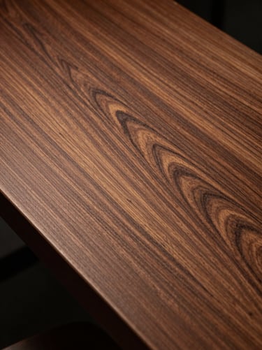 Vertical detail of rich black walnut wood grain, warm amber tones under low-key workshop lighting.