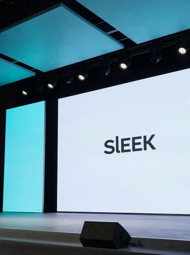 Sleek corporate stage setup with sharp LED screens, architectural cyan lighting, and minimal modern design under theatrical spotlights.