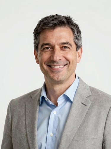 Professional headshot of a mature Italian male executive, smiling, neutral background, bright overcast daylight, soft corporate style, 35mm