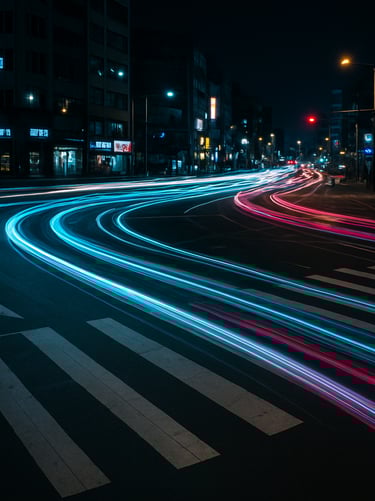 A long exposure night shot of a busy Korean urban intersection, with light trails of cars appearing as electric cyan and magenta ribbons against dark charcoal asphalt.