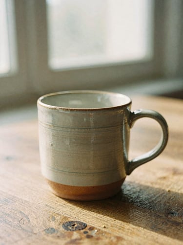 Close-up of a handmade ceramic mug on a rustic wooden table, soft morning window light, high texture detail, 35mm film.