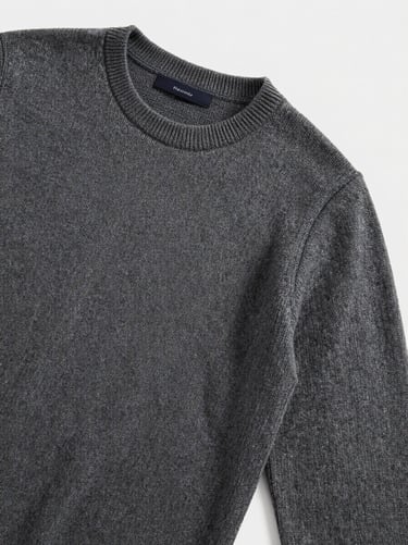 Editorial flat-lay of men's fine-gauge merino wool sweater in charcoal, soft natural light