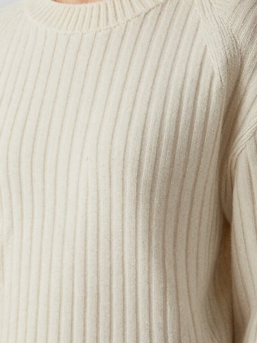 Editorial close-up of women's ribbed wool sweater in bone white, highlighting premium texture