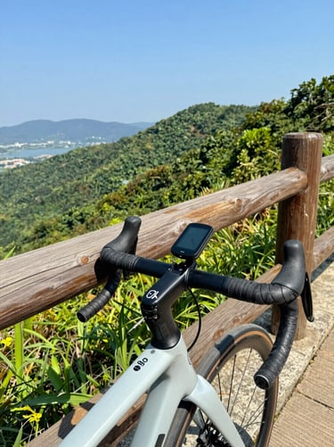 Close-up of a premium touring bicycle equipped with a GPS computer mounted on the handlebars, parked against a scenic wooden fence.