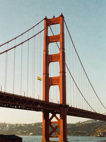 Saturated retro 35mm film photograph of San Francisco Golden Gate Bridge, bright pride flags waving, warm sunset light.
