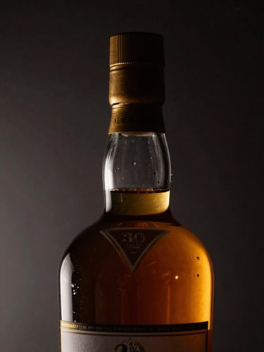 Chiaroscuro macro shot of The Macallan 30 Years Sherry Oak bottle neck and cork, warm amber liquid glow