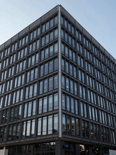 Architectural exterior photography of a modern commercial legal center in Monterrey, Mexico, featuring a structured dark glass and steel facade under crisp daylight, in slate blue and white tones.
