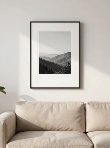 Straight-on eye-level shot of a modern minimalist living room wall with a black framed print hanging above a beige sofa, soft natural light