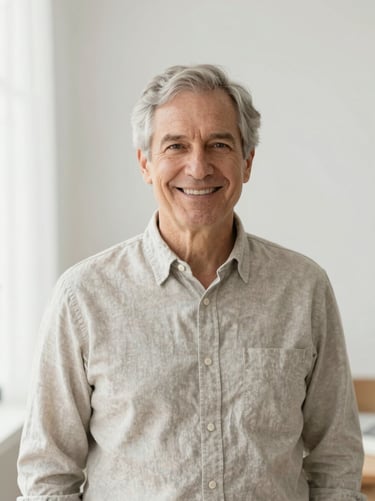 A professional portrait of a senior male consultant in a bright airy studio, soft morning light, warm approachable smile, neutral linen background