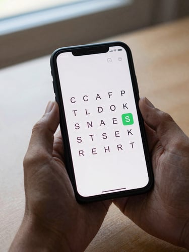 Hand holding an Android phone showing a simple word puzzle game screen at actual resolution, soft daylight from a nearby window, plain table background