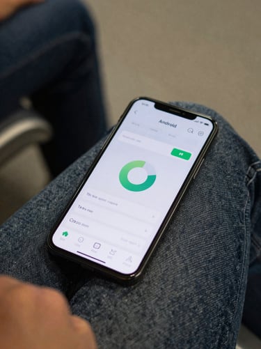 Android phone resting on a commuter's lap, screen showing a minimal battery-monitor app interface at actual resolution, ambient indoor transit lighting