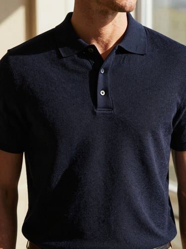 Man in a premium knit polo shirt, textured fabric, relaxed tailoring, warm natural window light.