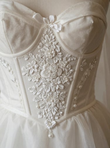 Extreme close-up of intricate hand-embroidered silk bridal bodice, white silk threads on ivory fabric, soft north-facing atelier light, no human face visible
