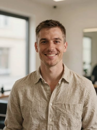 Portrait of a friendly male hair colorist with short hair, wearing a beige linen shirt in a warm-toned salon, soft window light, shallow depth of field.