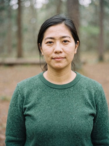 Candid portrait of a female community organizer in a forest green sweater, soft natural light, 35mm film grain