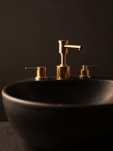 Close-up of a premium shampoo station with a black ceramic basin and gold-plated fixtures, dramatic low-key lighting