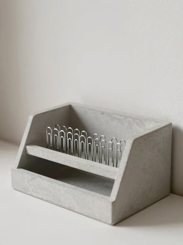 A heavy concrete desk organizer holding steel paperclips, soft side daylight