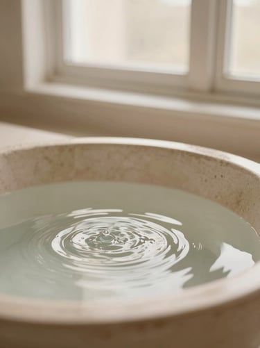 Soft water ripples in a beige stone basin under morning light, portrait aspect