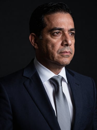 Professional close-up portrait of Lic. Leopoldo Guzmán Ramirez, a corporate lawyer in a dark tailored suit and steel-grey tie, serious expression, dramatic side lighting, high contrast, 35mm.