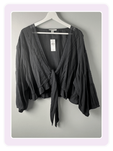 Black American Eagle boho tie-front crop top with lace trim and long balloon sleeves on a hanger.