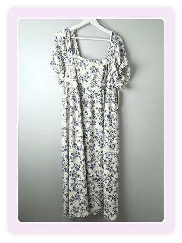 White midi dress with a blue floral pattern and ruffled short sleeves on a white hanger.
