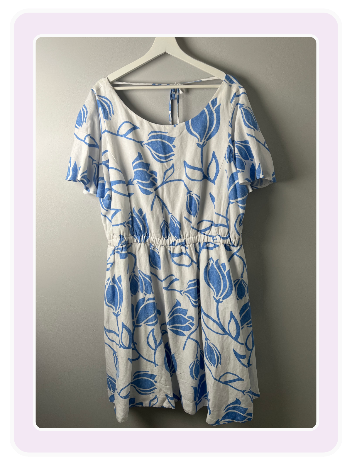 LB White short-sleeve summer dress with a blue floral tulip print and elastic waist on a hanger.
