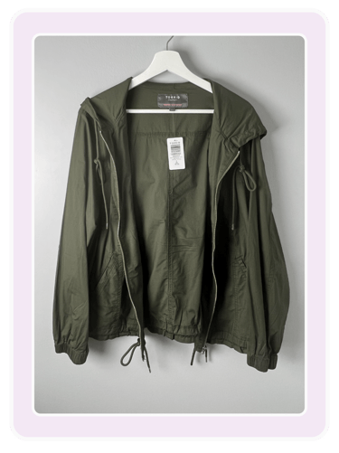 Torrid olive green hooded utility jacket with full zip and drawstring waist on a white hanger.