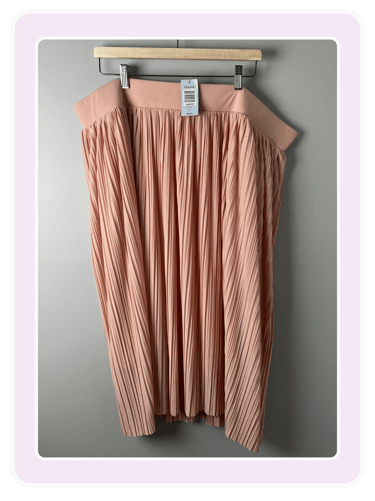 Torrid rose gold pleated midi skirt with an elastic waistband hanging on a wooden clip hanger.