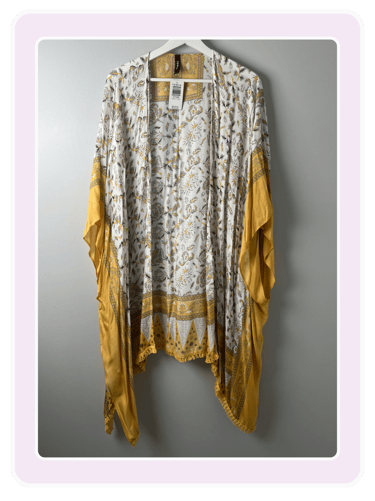 Torrid yellow and white floral print kimono cardigan with fringe trim hanging on a white hanger.