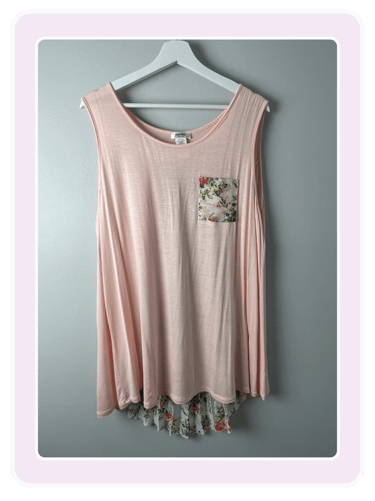 Pink sleeveless tunic top featuring a floral pocket and matching floral ruffle hem on a white hanger.