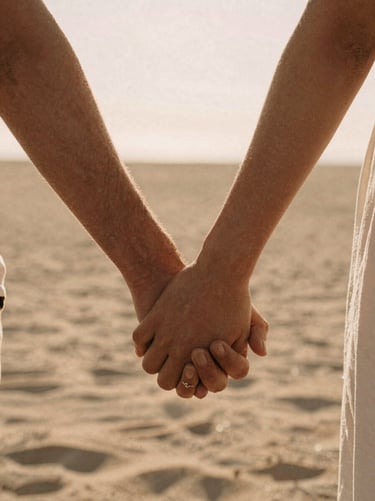 Intimate close-up of a couple's hands intertwined, warm backlighting, soft sand tones, cinematic 35mm film aesthetic